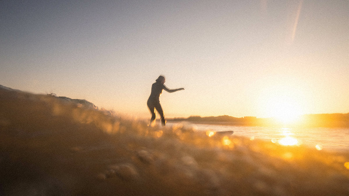 Frau surft eine Welle vor Sylt